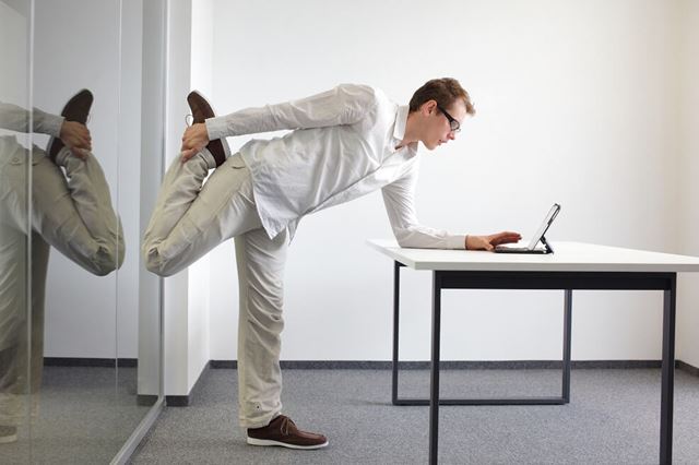 Man standing up and stretching at his desk